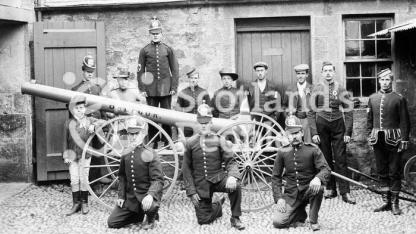Volunteer firemen and estate workers with a pump mounted on wheels, c 1905