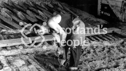 Workman breaking ingots from mould, Carron Works, 20th century