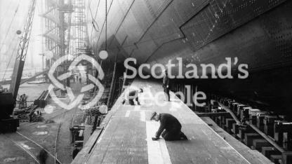 Workmen preparing the launching ways of the Cunard Line ocean liner Queen Mary