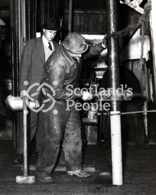 Men removing drilled core on boring tower in the Forth, 1955