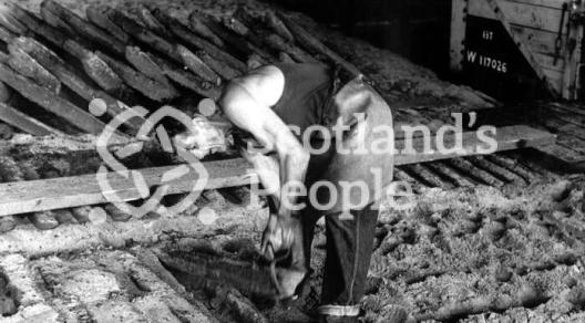 Workman breaking ingots from mould, Carron Works, 20th century