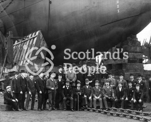 Staff of J & G Thomson posing before the bow of HMS Ramilies on the slip way on the day of the launch.