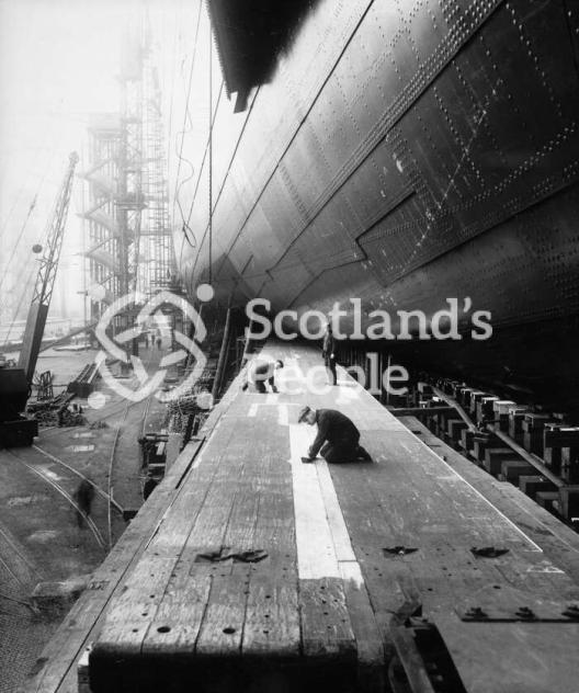 Workmen preparing the launching ways of the Cunard Line ocean liner Queen Mary