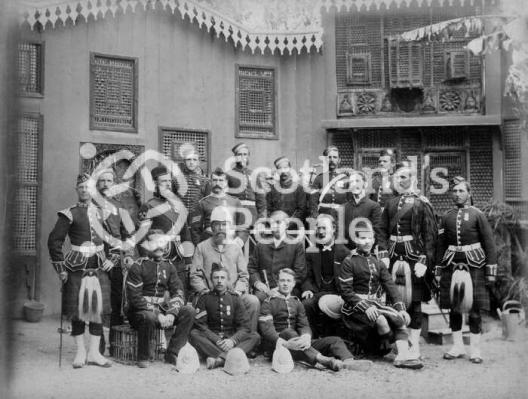 Officers and men of [The Black Watch, (Royal Highlanders)] standing in front of Egyptian vernacular building.